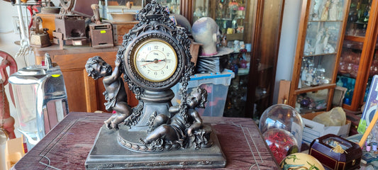 El reloj de mesa de plástico de la marca Crosa con temática de querubines - Antiques Bazaar Ensenada